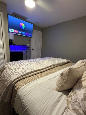 Quarto com cama, televisão na parede e uma porta.
