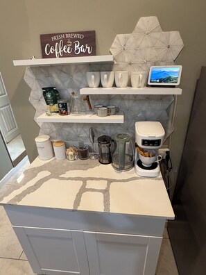 Cozinha com bancada para café, incluindo cafeteira, canecas e grãos de café.