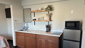 A compact kitchen with a sink, wooden cabinets, a countertop, a microwave, and a refrigerator. - Room 20. Angry Salmon Inn. (Anchor Point)