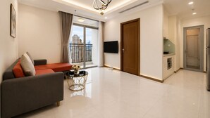 Een moderne woonkamer met een bank, een salontafel, een televisie en een balkon met uitzicht op de stad.