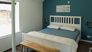 A bedroom with a white bed, a wooden bench, a blue wall, and a window. - 5 bedroom nice home in Schalkhaar (Schalkhaar)