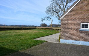 Ein Backsteinhaus mit Fenster und Tür, ein Rasen und ein Hecken.