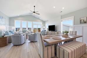 Ein geräumiges Wohnzimmer mit Essbereich, großen Fenstern und einem Deckenventilator.