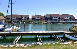 A marina with boats docked, a wooden pier, and row houses with red roofs. - Amazing apartment in Borre with house sea view (Borre)