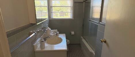 Ein kleines Badezimmer mit einem weißen Waschbecken, einem Spiegel und einer Dusche.