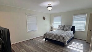 Un dormitorio con una cama, ventilador de techo y televisor.