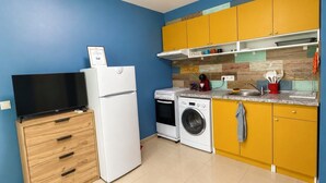 Une cuisine compacte équipée d’un téléviseur, d’un réfrigérateur, d’un lave-linge et d’un four à micro-ondes.