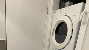 A laundry room with two stacked front-loading washing machines and a door.