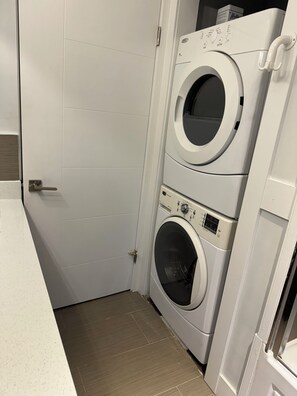 A laundry room with two stacked front-loading washing machines and a door.