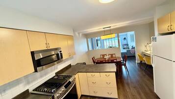 Uma cozinha moderna com fogão a gás, micro-ondas e armários. Há uma área de refeições com mesa e cadeiras.