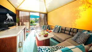 Ein Zimmer mit Fernseher, der das MGM Grand Logo zeigt, einer Couch mit Leopardenmuster-Kissen und einem Essbereich mit Tisch für zwei Personen.