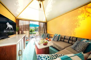 A room with a television displaying the MGM Grand logo, a sofa with leopard print cushions, and a dining area with a table set for two. - MGM Signature Suite - Strip & Sphere View - NO Resort Fee (Las Vegas)