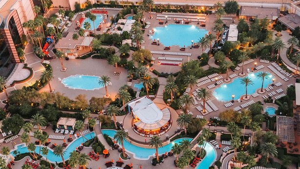Ein Resort mit mehreren Schwimmbecken, Palmen und Liegebereichen.