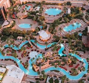 A resort with multiple swimming pools, palm trees, and lounge areas. - MGM Signature Suite - Strip & Sphere View - NO Resort Fee (Las Vegas)