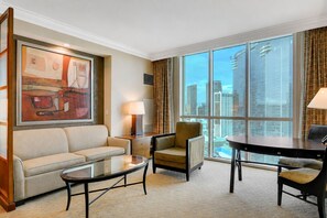 A hotel room with a large window, a sofa, a chair, a small table, and a painting. - MGM Signature Suite - Strip & Sphere View - NO Resort Fee (Las Vegas)