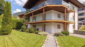 A multi-story building with a wooden facade, balconies, and a well-maintained garden. - Stylish apartment with sauna, by the slopes (Brixen im Thale)
