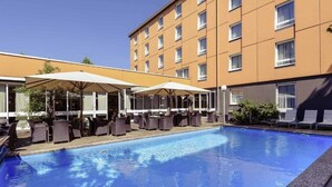 Un hotel con piscina, asientos al aire libre y un edificio de varios pisos.
