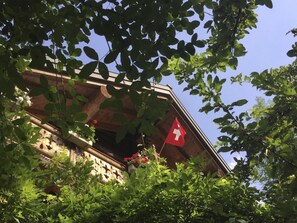 En bygning med balkon, omgivet af grønt.