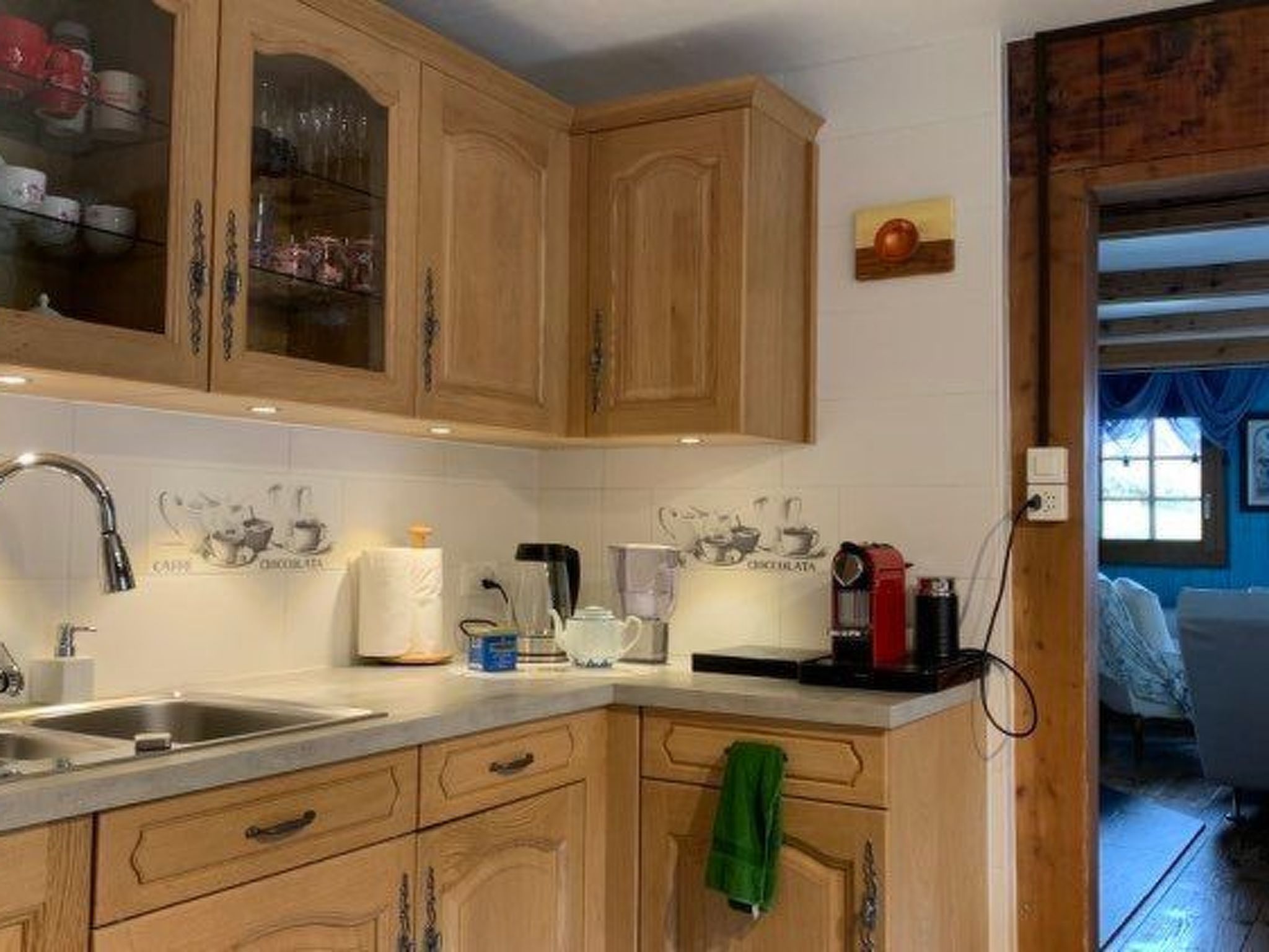 A kitchen with wooden cabinets, a sink, and various appliances including a coffee maker and a kettle.
