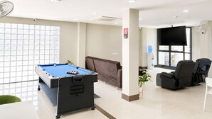 Una mesa de billar, un sofá, un televisor y una zona de estar con sillas.