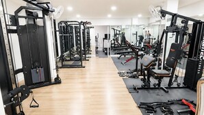 Un gimnasio con equipo de ejercicio diverso, suelo de madera y espejos en las paredes.