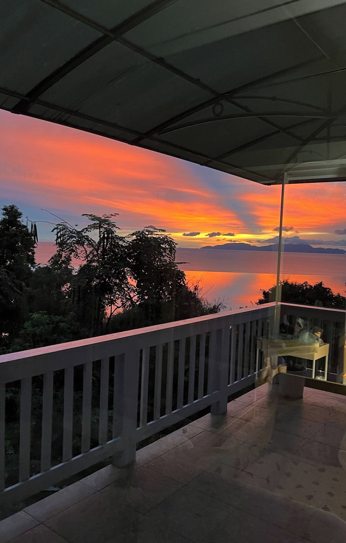Un balcón con vistas a un atardecer sobre el agua.