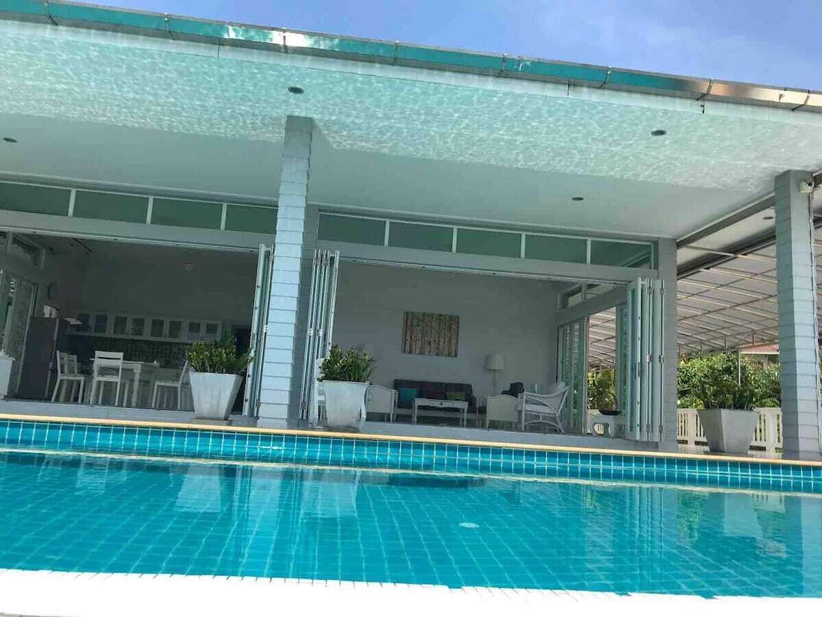 Une piscine dotée d’un espace abrité, de chaises et d’une table.