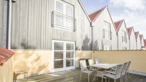 A wooden deck with a table and chairs, a sliding glass door, and a building with a red-tiled roof. - "Ehlin" - 900m from the sea by Interhome (Skagen)