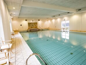 Ein Schwimmbad mit gefliestem Boden, einer Bank und einem Stuhl in Poolnähe.