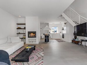 A modern living room with a fireplace, a dining area, and a kitchen with a large TV. - "Ehlin" - 900m from the sea by Interhome (Skagen)