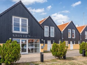 Une rangée de bâtiments modernes à la façade sombre et aux toits recouverts de tuiles orange.