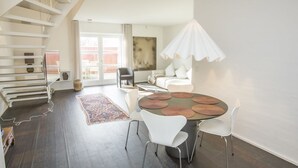 A modern living space with a staircase, a dining area with a round table and chairs, a sofa, and a large window. - "Ehlin" - 900m from the sea by Interhome (Skagen)