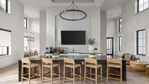 Una cocina amplia con una isla grande, iluminación colgante moderna y un televisor de pantalla plana montado en la pared.
