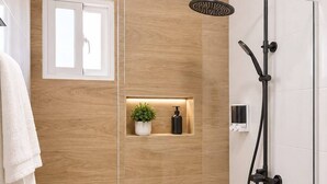 A modern shower area with a glass enclosure, a handheld showerhead, and a wall-mounted faucet.