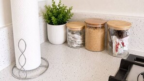 A kitchen corner with a paper towel holder, a potted plant, and three glass jars with lids.