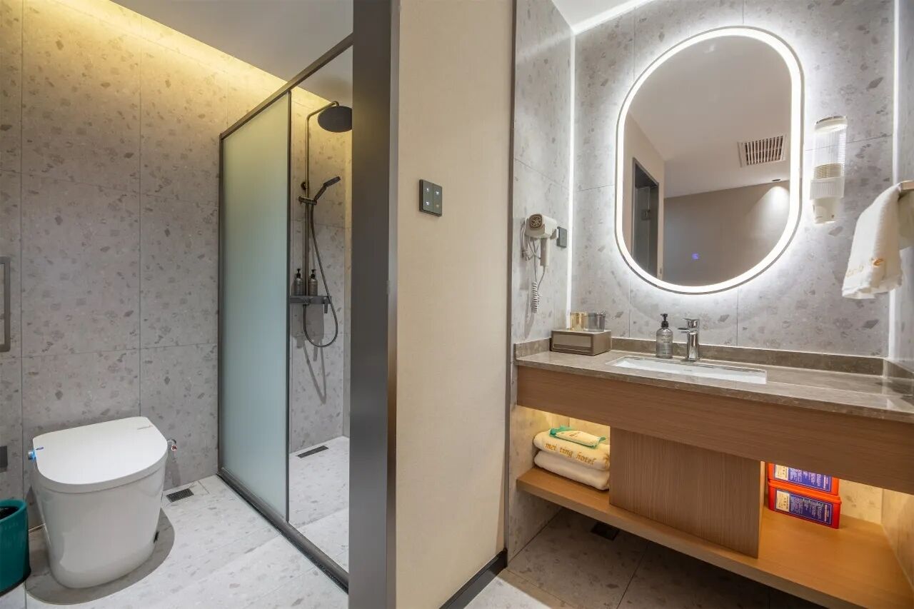 Un baño moderno con ducha de vidrio, tocador con espejo y retrete.