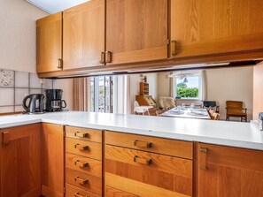 Eine Küche mit Holzschränken, einer Kaffeemaschine und einem Essbereich mit Tisch und Stühlen.