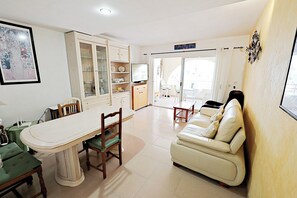 A dining area with a table and chairs, a sofa, a cabinet with glass doors, and a television. - Sabine - apartment located in the heart of Calpe (Calpe)