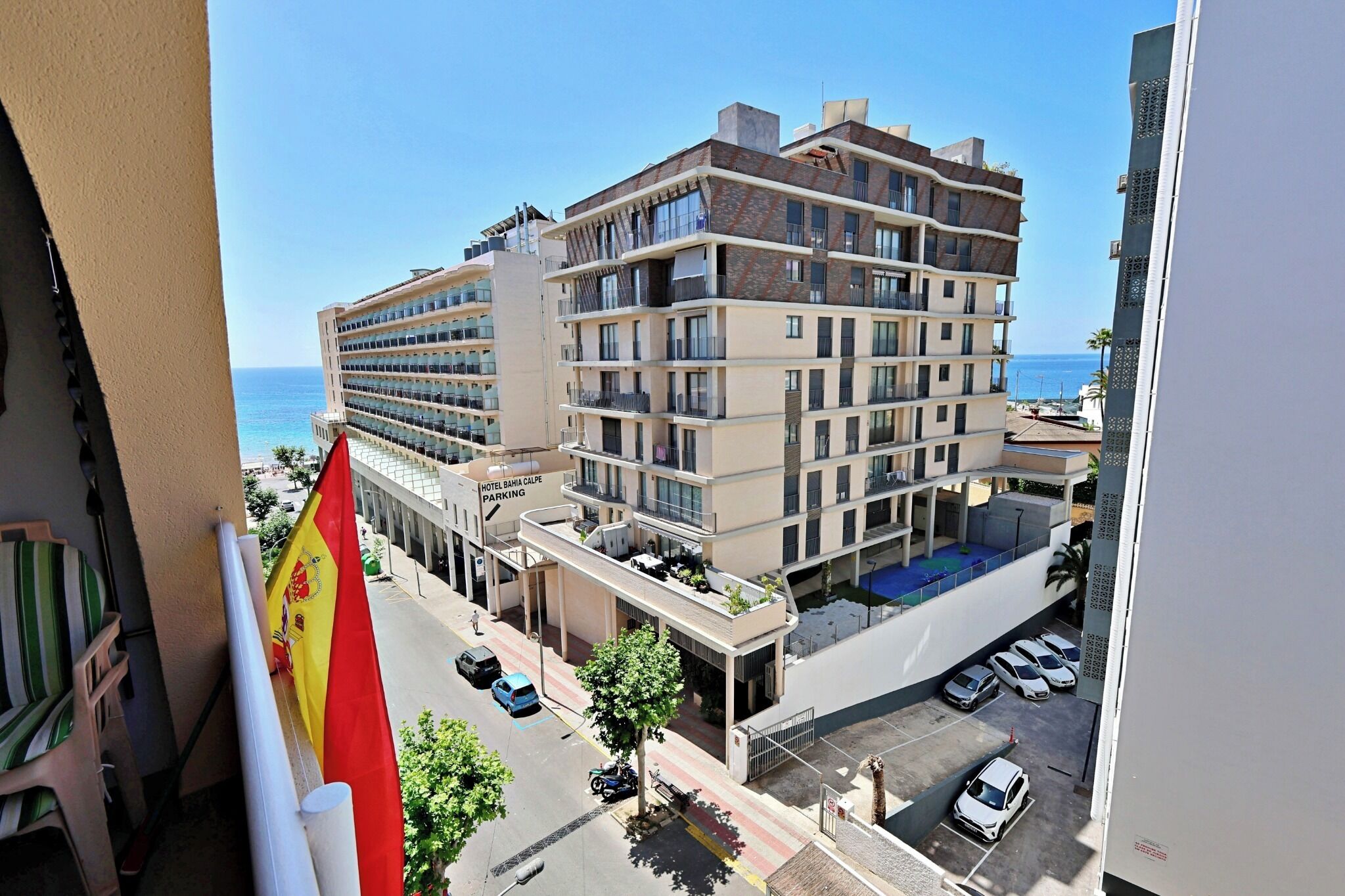 Um hotel de vários andares com varandas, área de estacionamento e vista para o mar.