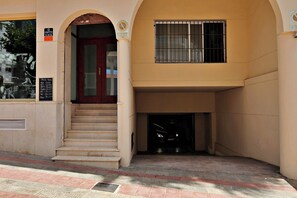 A building entrance with a red door, a staircase, and a window with bars. - Sabine - apartment located in the heart of Calpe (Calpe)
