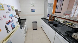 Eine Küche mit weißen Schränken, einer schwarzen Arbeitsplatte, einem Spülbecken und einem Mülleimer.