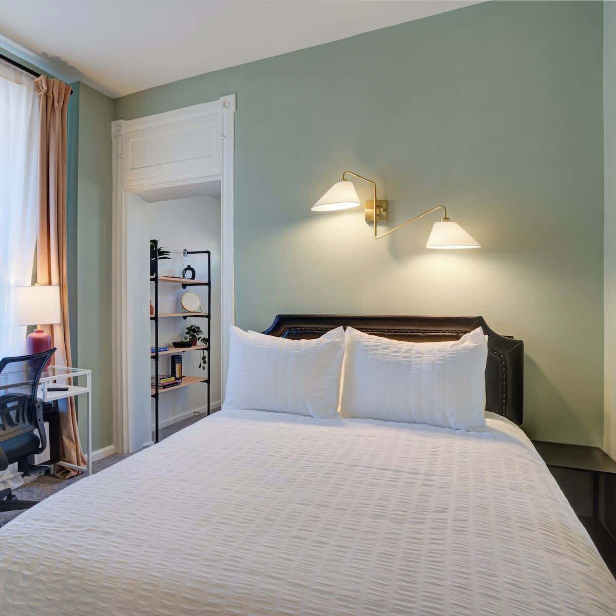 Ein Hotelzimmer mit Bett, Nachttischlampen, Schreibtisch und Stuhl.