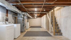 Un cuarto de lavandería con lavadoras, una secadora y una escalera que sube a un nivel superior.
