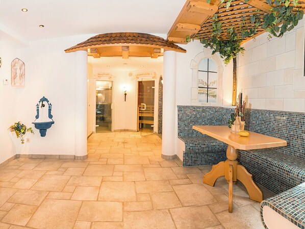 Una habitación con un banco a cuadros, una mesa y una planta colgante.
