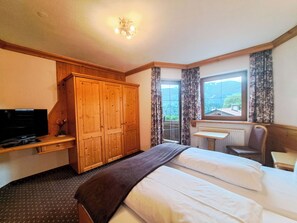 Ein Hotelzimmer mit einem Bett, einem Schreibtisch mit Stuhl, einem Fernseher und einem Kleiderschrank.