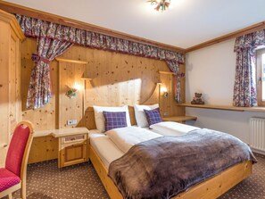 Ein Schlafzimmer mit Holzwänden, einem Bett, Nachttischen, einem Sessel und Vorhängen.