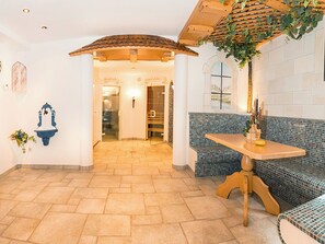 Ein Zimmer mit einer karierten Bank, einem Tisch und einer hängenden Pflanze.