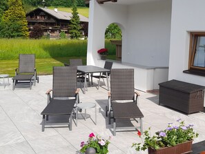 Eine Terrasse im Freien mit Korbmöbeln, einem Tisch und Topfpflanzen.