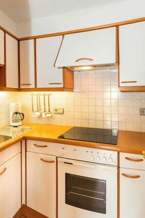 Una cocina con armarios blancos, estufa, horno y encimera.