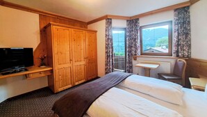 A hotel room with a bed, a desk with a chair, a television, and a wardrobe. - Schatzberg by Interhome (Auffach)